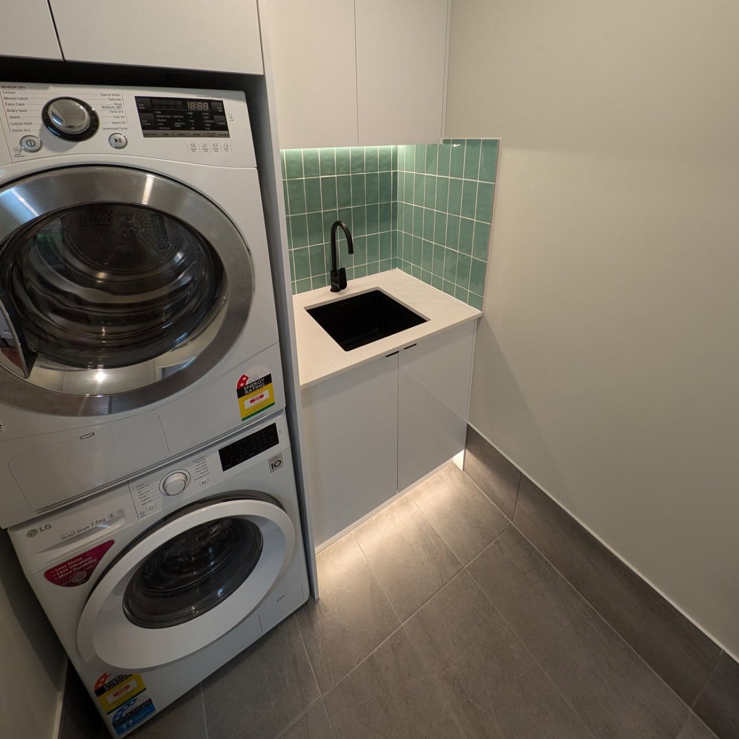 Renovated laundry with green feature splashback and stone benchtop